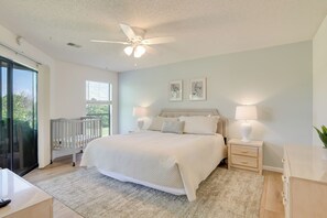 A bedroom with a large bed, two bedside tables with lamps, a ceiling fan, and a view through a sliding glass door. - Lil' Slice of Heaven on Hole 11' Branson Condo! (Branson)