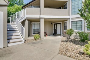 A two-story building with a covered entrance, a staircase, and a small garden area with rocks and plants. - Lil' Slice of Heaven on Hole 11' Branson Condo! (Branson)