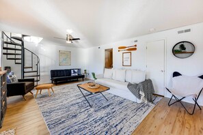Relax in this stylish living space with a curved staircase, comfortable sofa, and unique armchair.