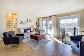 Relax in this stylish living room with a sofa, armchairs, and a balcony view.