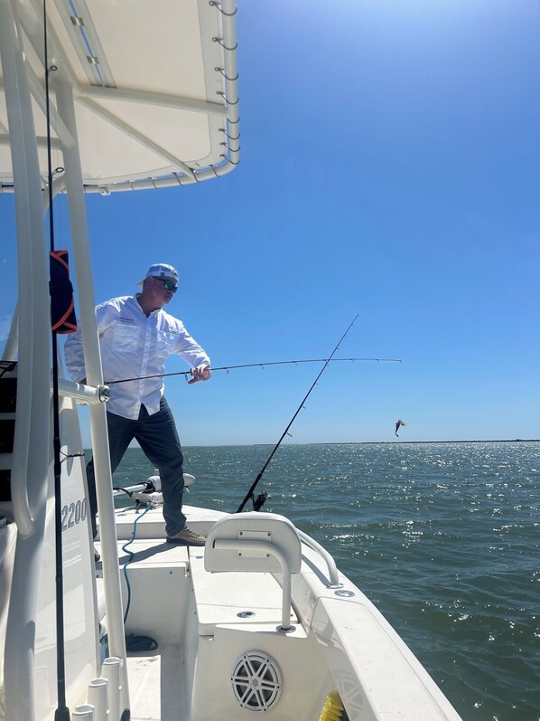 A boat with a person fishing, a clear sky, and calm water. - Come out and enjoy Autumn at the HH Ranch on Smith Island. (Smith Island)