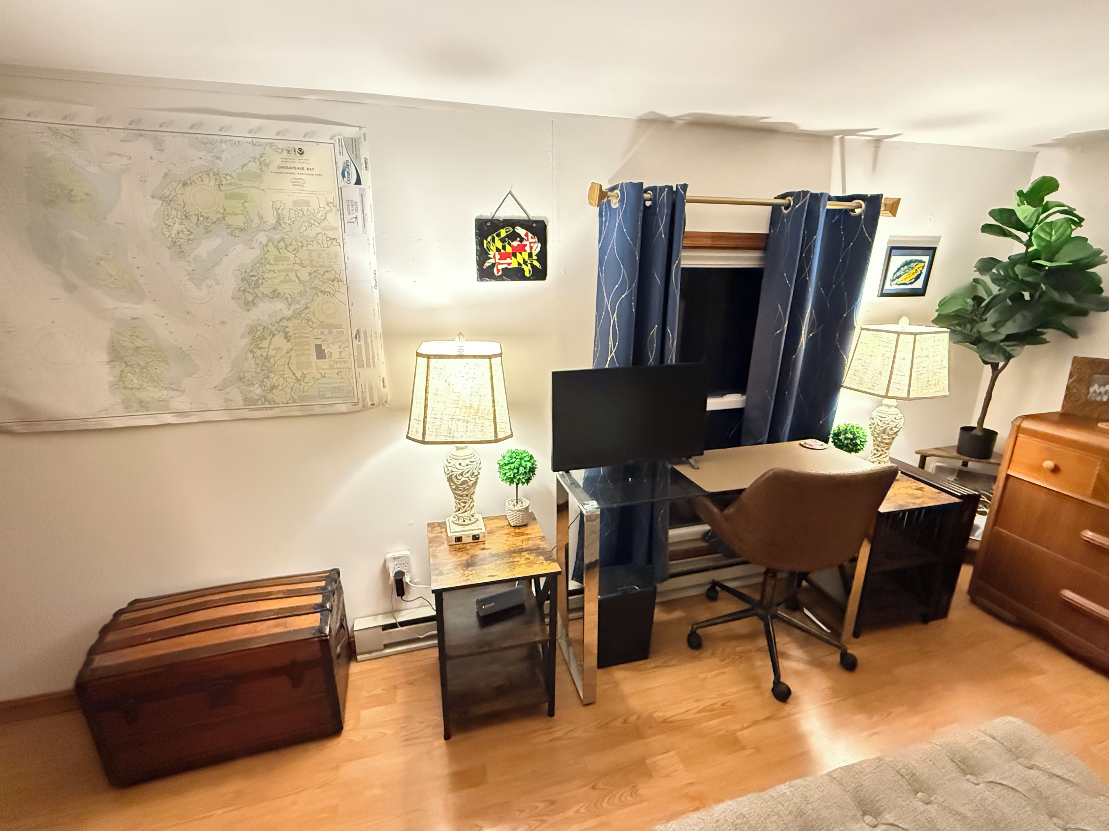 A compact living space with a desk, chair, computer, and a map on the wall.