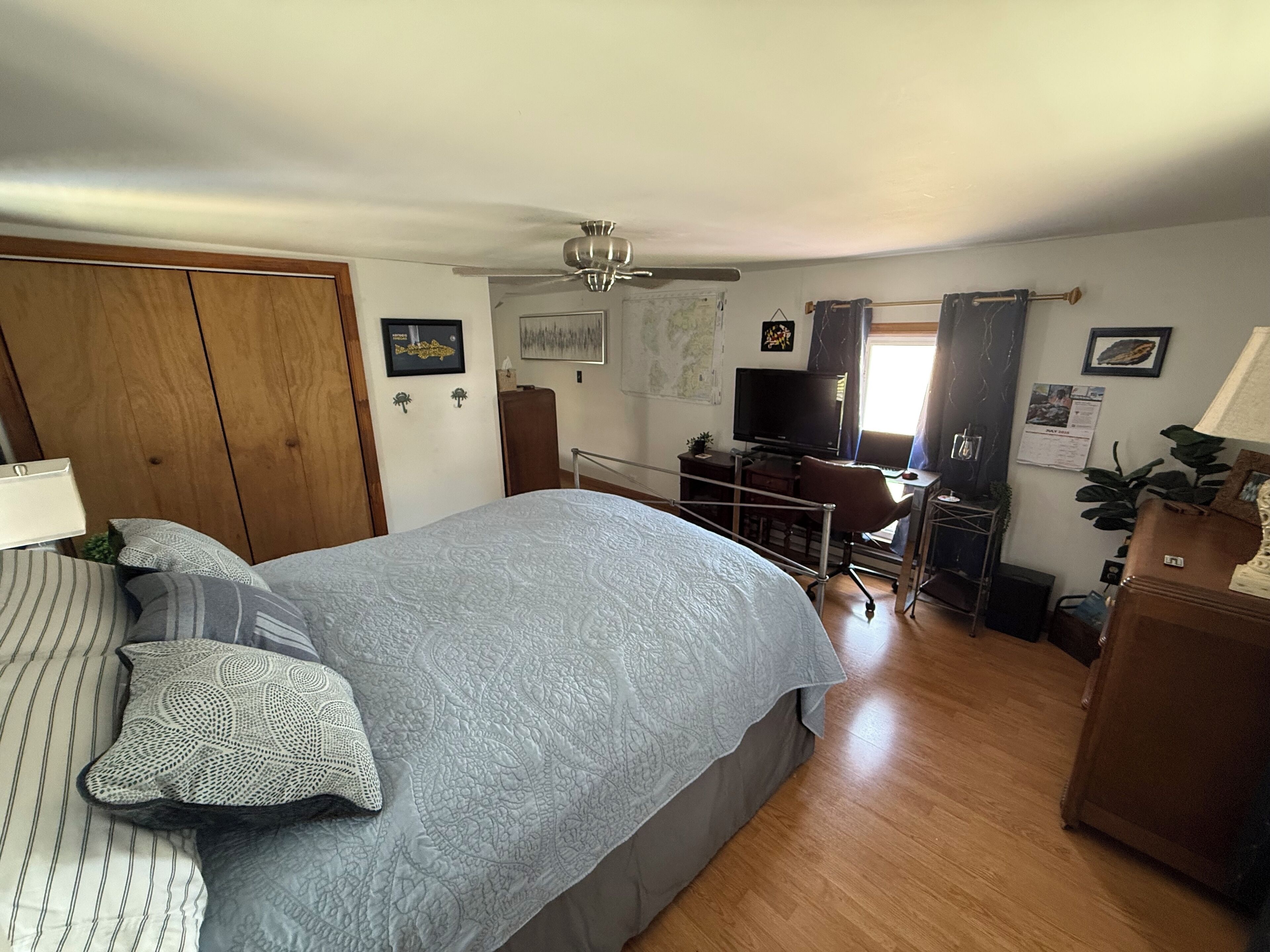 A bedroom with a bed, a desk, a television, and a wardrobe.