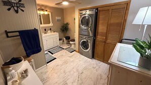 Un baño moderno y funcional con lavamanos, espejo y dos lavadoras apiladas.