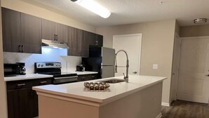 Una cocina moderna con armarios oscuros, encimera blanca y una isla central.