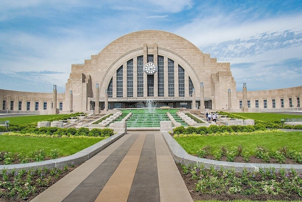 A large building with a central clock tower, a fountain, and a symmetrical garden layout.