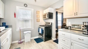 A compact kitchen with white cabinets, a stove, microwave, and a toaster.