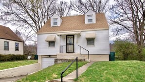 A two-story house with a front porch, a small front yard, and a stone retaining wall.