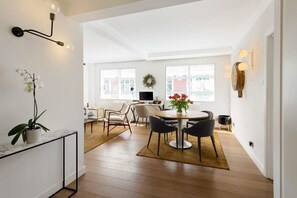A modern living room with a dining area, a potted orchid, and a view of the city through large windows. - Immaculate 2-bed House in London, Mayfair (London)