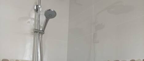Une douche équipée d’un pommeau de douche à main et d’un pommeau de douche mural en forme de pluie.