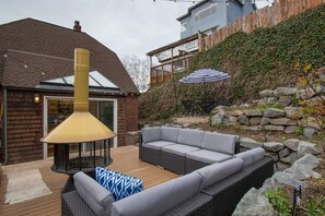A patio with a large chimney, outdoor furniture, and a stone wall. - Green Lake Oasis with Loft + Outdoor Fireplace (Seattle)