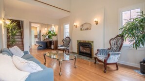 Un salón amplio con chimenea, un sofá azul, una mesa de centro de vidrio y dos sillones.