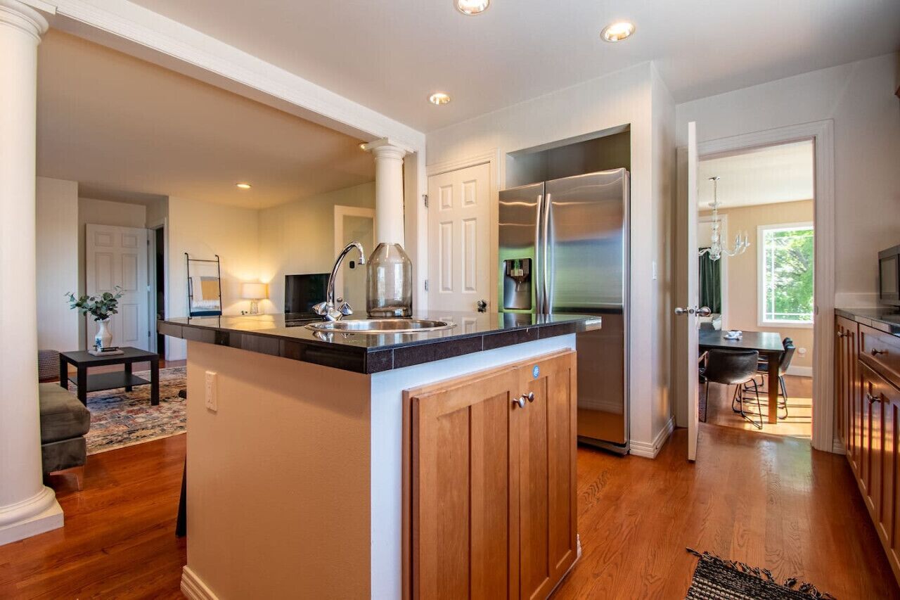 A modern kitchen with a central island, stainless steel appliances, and a dining area with a table and chairs.