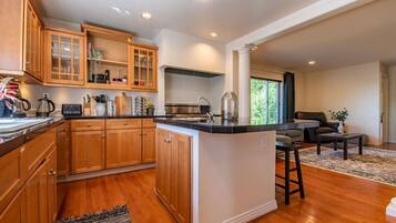A modern kitchen with wooden cabinets, a central island, and a dining area with a sofa and coffee table.
