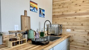 Une cuisine compacte dotée de plans de travail en bois, d’une machine à café, d’une bouilloire et d’un évier.