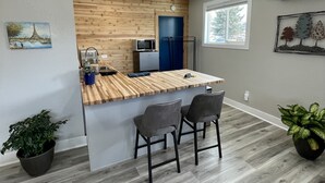 Une cuisine moderne avec un îlot central en bois, des tabourets de bar et un four à micro-ondes.