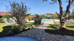 Uma trilha de pedra leva a uma área de piscina, com uma bicicleta e uma árvore em primeiro plano.