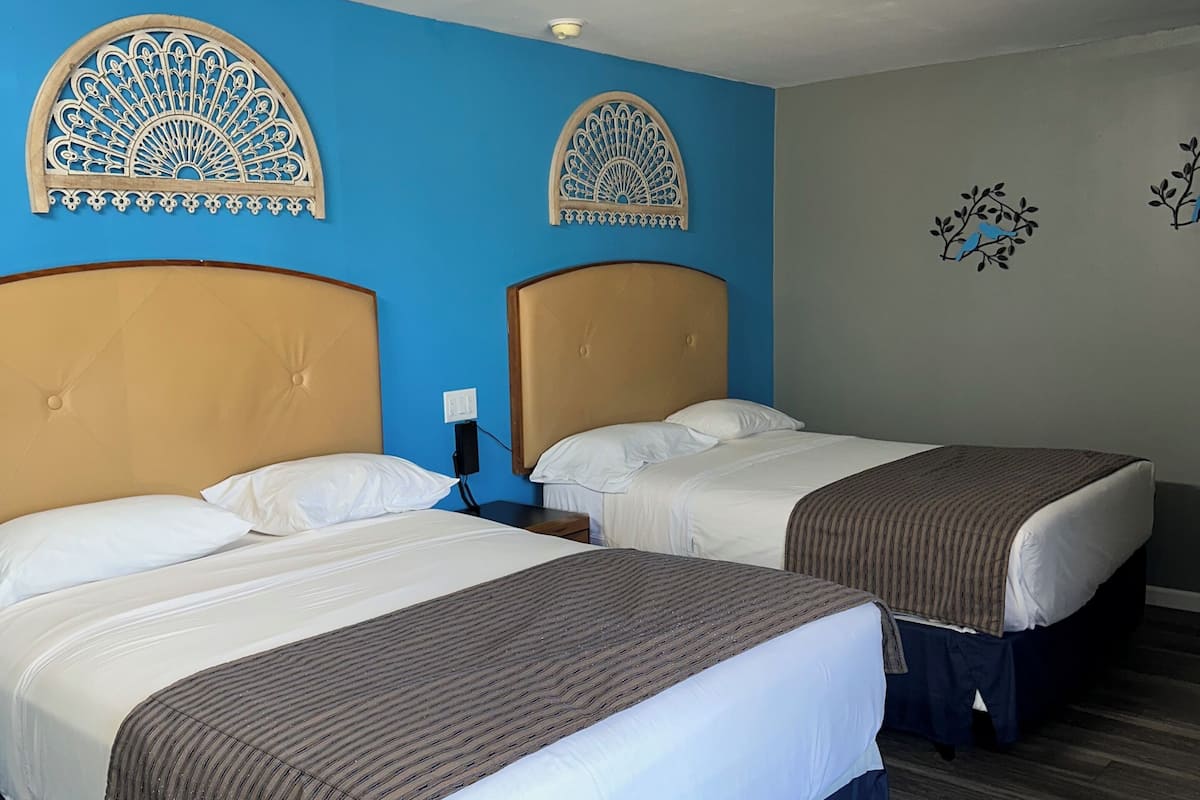 A hotel room with two beds, each with a headboard and a brown bedspread.