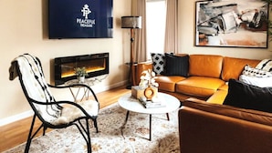 A modern living room with a leather sofa, a fireplace, a flat-screen TV, and a large abstract painting. - Peachtree/Royal Oak`s Sweet Spot/King Bed (Royal Oak)