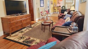 A living room with a television, sofa, coffee table, and a decorative rug.