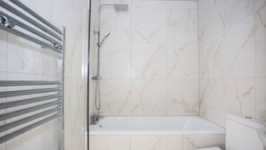 Een badkamer met bad, toilet en douche.