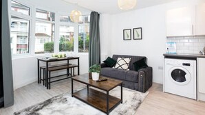 Eine moderne Wohnung mit Essbereich, Sofa, Couchtisch und Waschmaschine.
