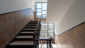 Ein modernes Interieur mit einer Treppe, Marmorwänden und Blick auf ein Gebäude durch große Fenster.