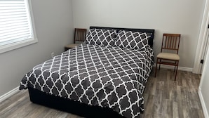 A bedroom with a bed, two chairs, a window, and a door. - Home away from Home
Main Floor of Home (Three Hills)