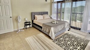 A bedroom with a bed, a standing fan, a nightstand, and a window with curtains. - Lavish 1 bedroom in St. George (Belmont)