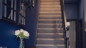 A staircase with a dark wall and a vase of white flowers on a console table. - Margate Beach house (Cliftonville)