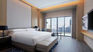 A modern hotel room with a large bed, a desk, a chair, and a large window offering a city view. - Courtyard by Marriott Foshan (Foshan)
