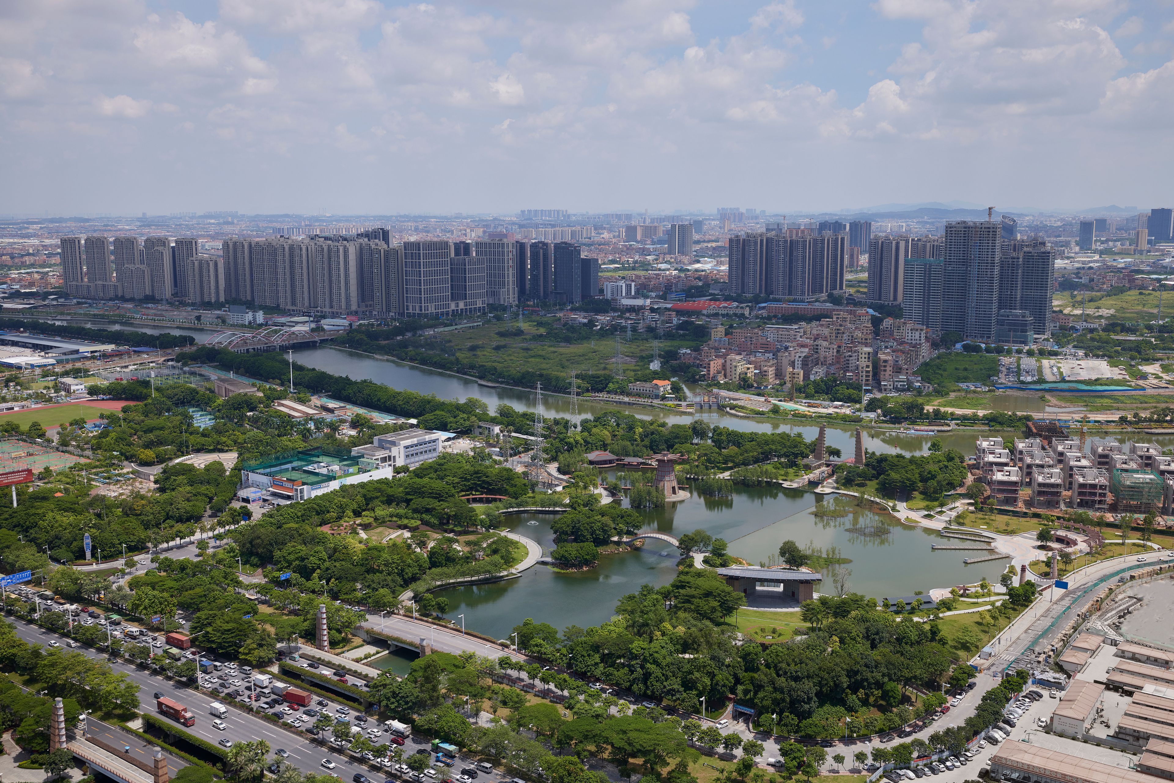 A cityscape with high-rise buildings, a river, and a park with a lake.