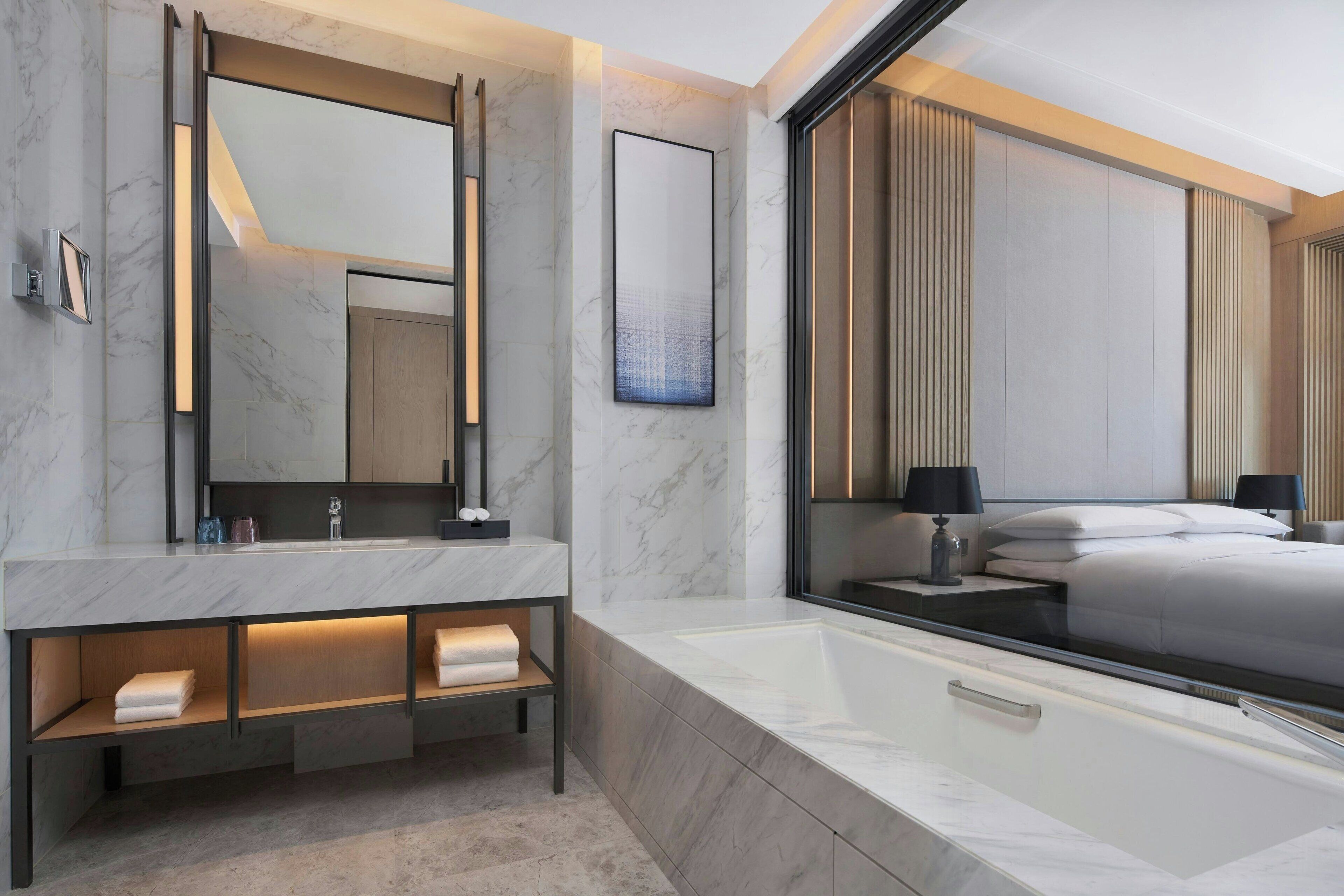 Un baño moderno con un espejo grande, una bañera y un tocador con repisas.