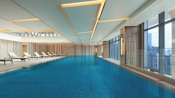 A modern indoor swimming pool with a long, narrow design, surrounded by lounge chairs and large windows offering views of the city. - Courtyard by Marriott Foshan (Foshan)