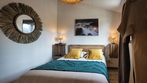 A bedroom with a large bed, two bedside lamps, a round mirror, and a framed picture on the wall. - Magnificent T3 behind the dune (Lacanau)