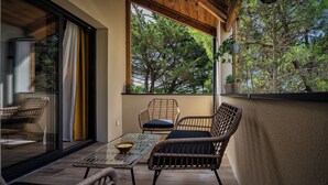 A balcony with wicker furniture, a glass table, and a view of trees. - Magnificent T3 behind the dune (Lacanau)