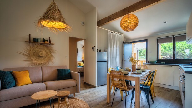 A modern living space with a sofa, dining table, chairs, and a kitchen area. - Magnificent T3 behind the dune (Lacanau)
