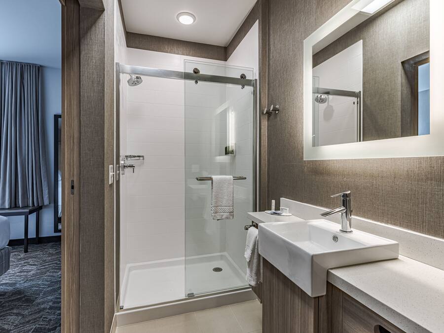 A modern bathroom with a glass-enclosed shower, a sink, and a mirror.