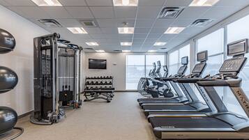 A gym with treadmills, weight machines, and a TV screen.