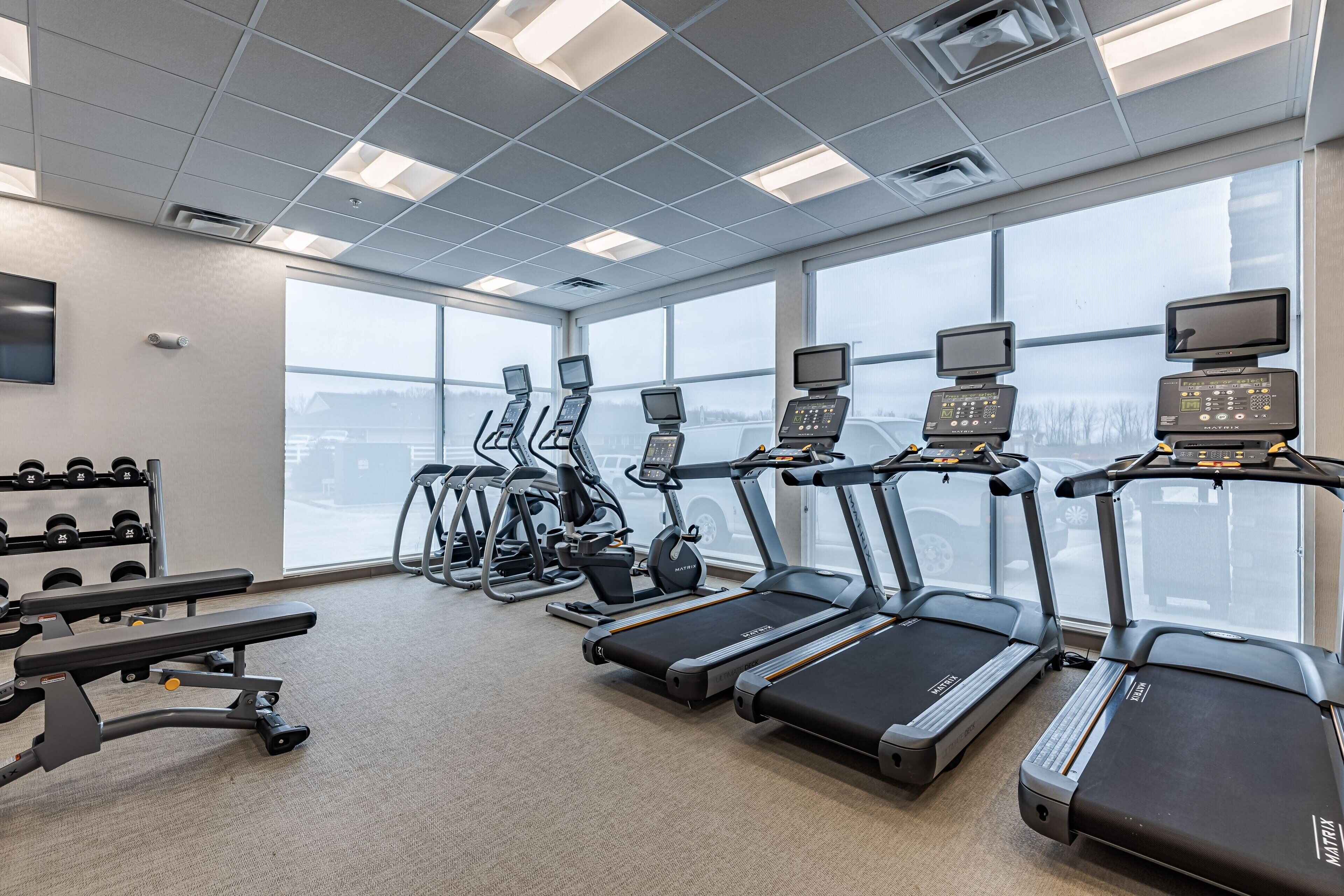 Un gimnasio con cintas de correr, elípticas y bancos de pesas.
