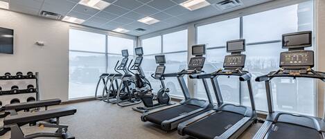A gym with treadmills, elliptical machines, and weight benches.