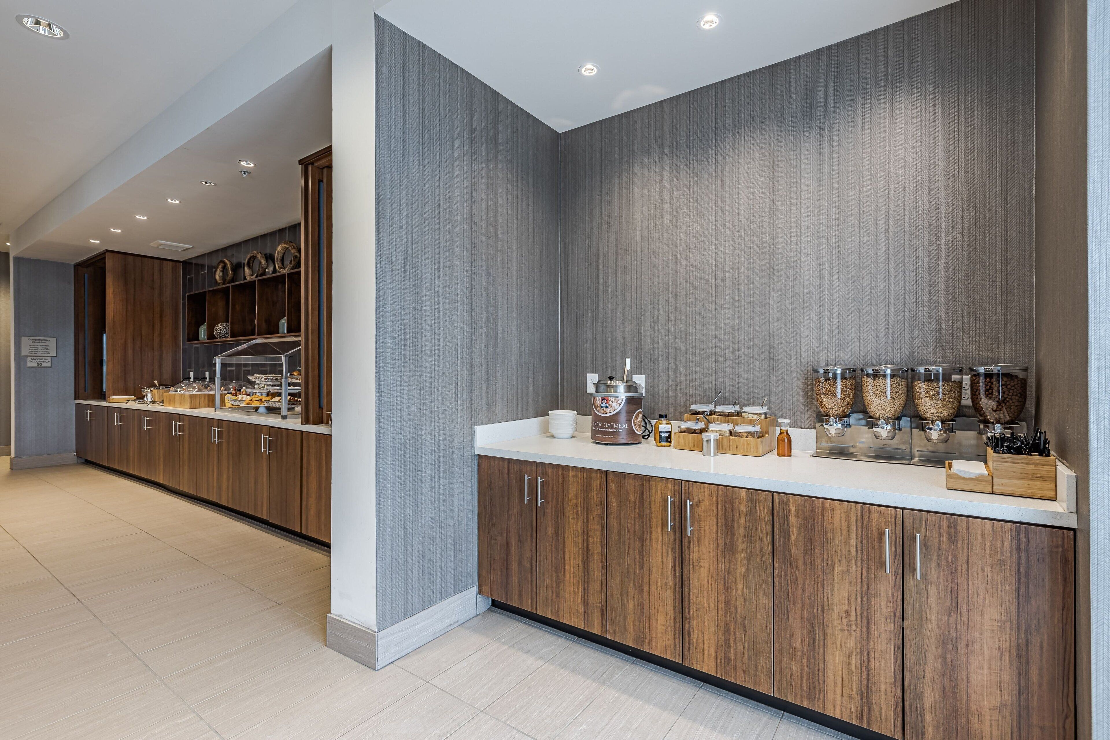 Una cocina moderna con armarios de madera, encimera blanca y una zona de café.