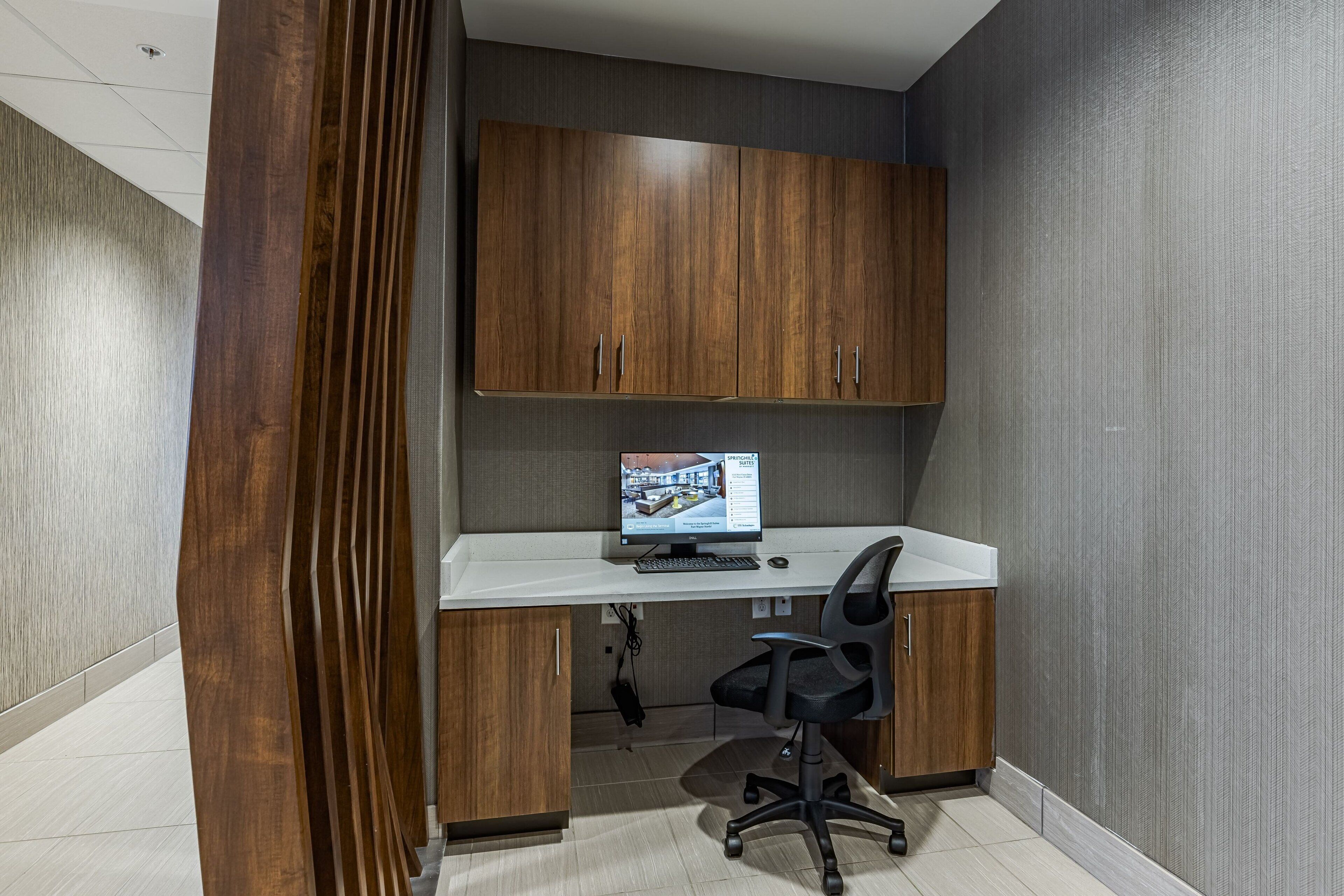 A modern office space with a white desk, a computer, and a black office chair.