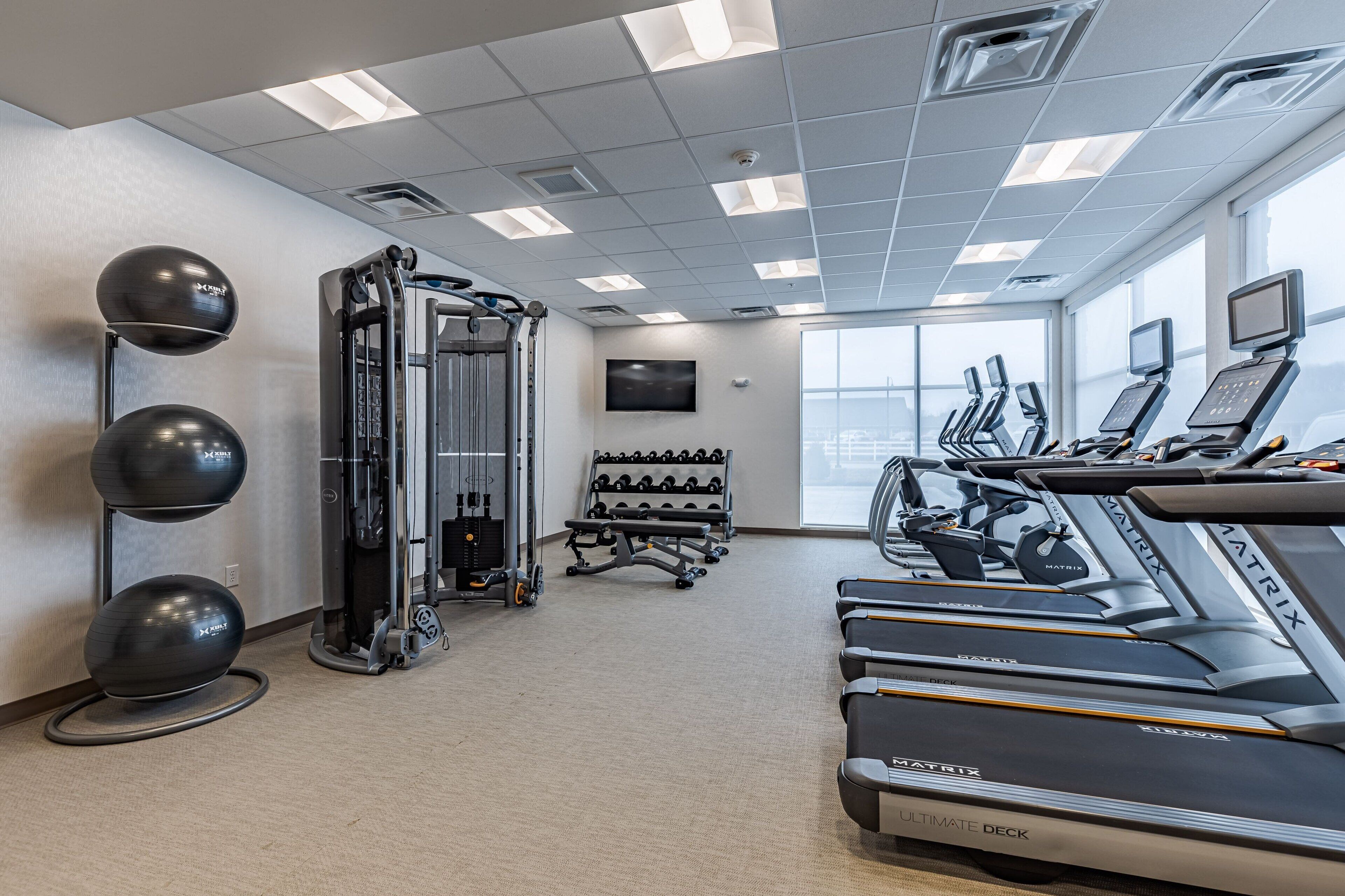 A gym with treadmills, weight machines, and exercise balls.