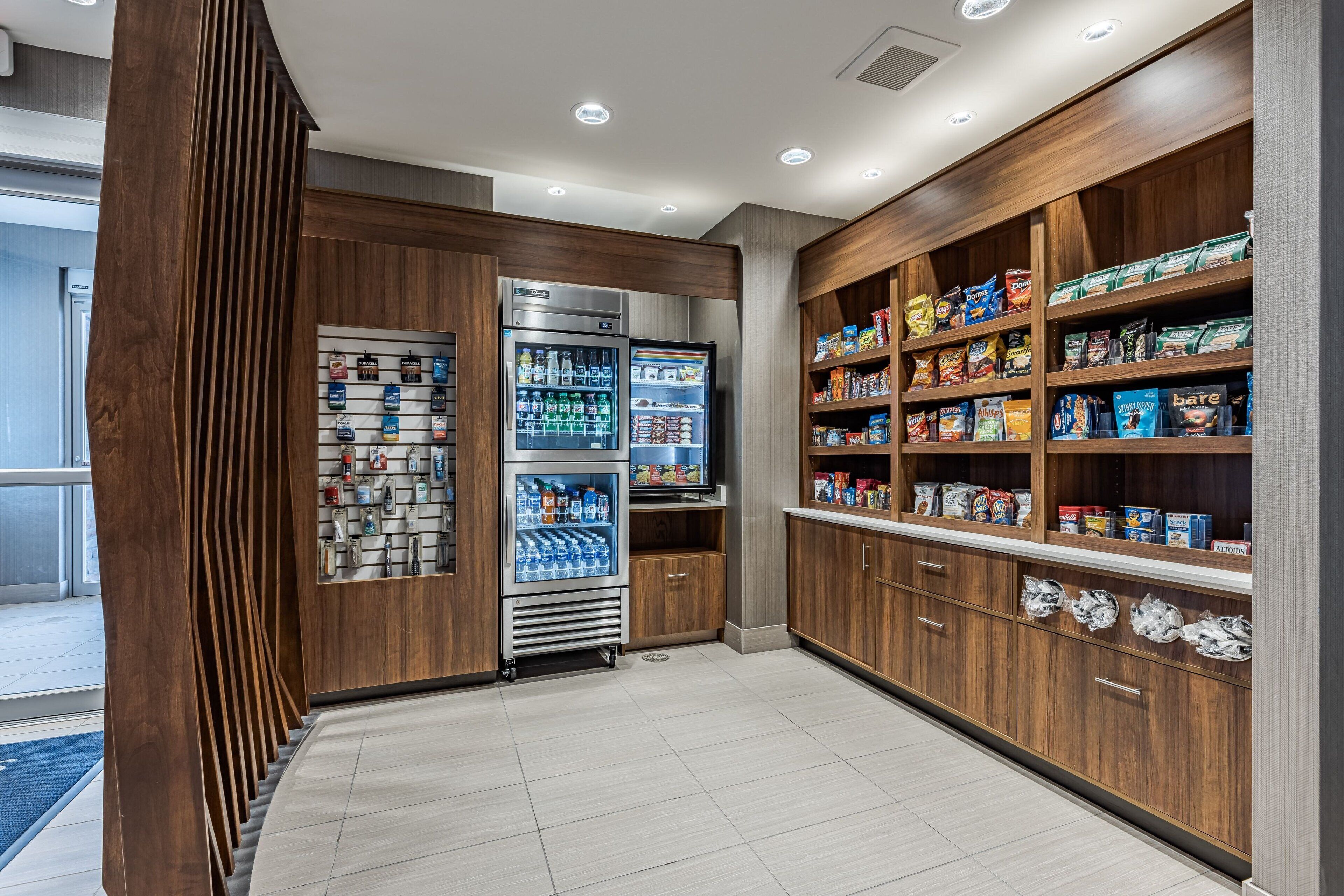 A well-lit snack bar with refrigerated drinks and a variety of snacks.