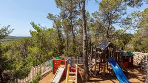 Un parque infantil con toboganes y estructuras para escalar, rodeado de árboles.