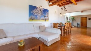 Una sala de estar con un sofá, una mesa de centro de madera y un cuadro con árboles.