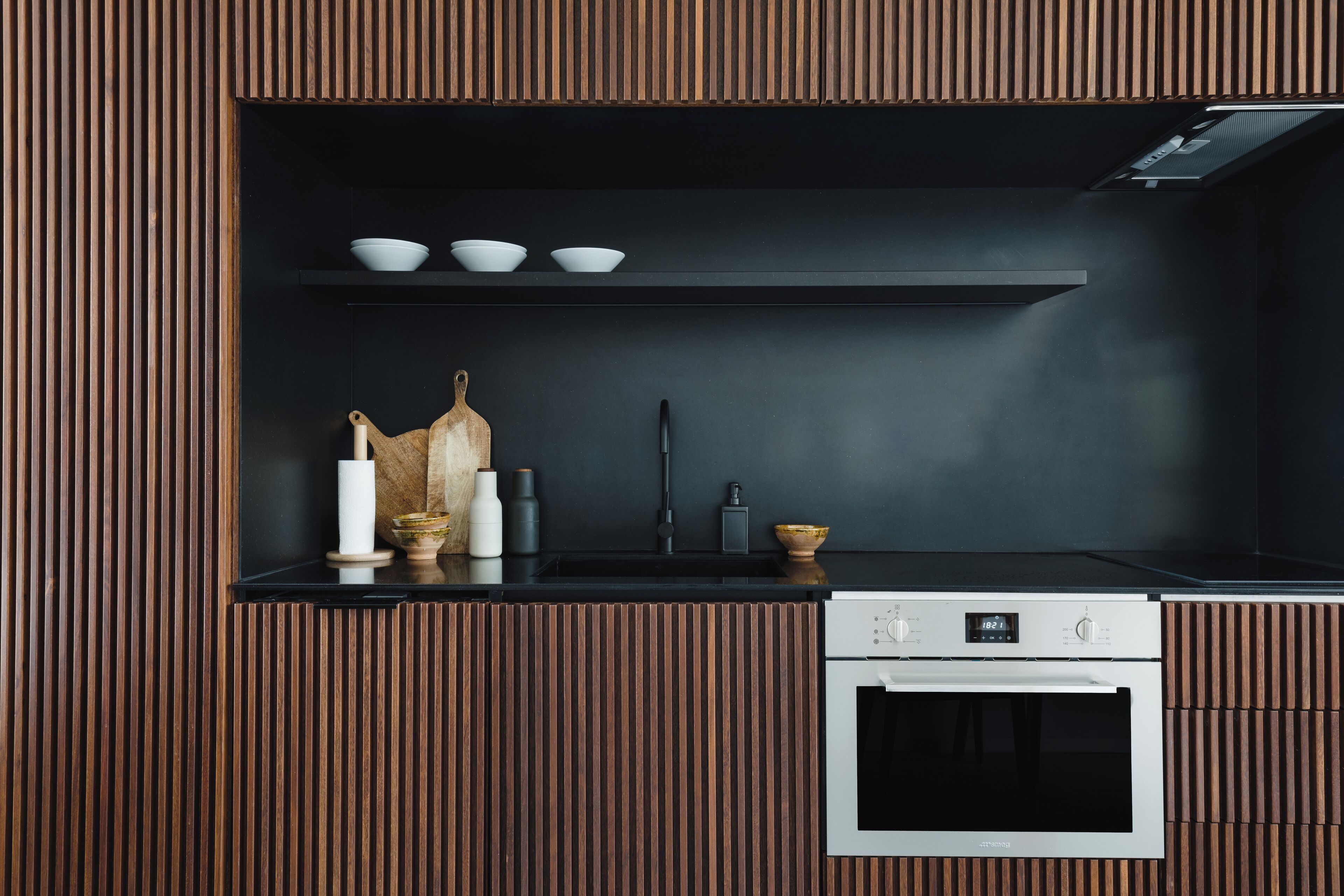 Una cocina moderna con horno empotrado y encimera negra.