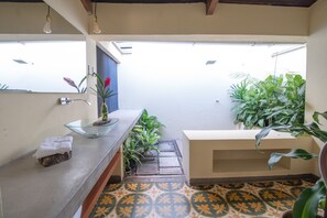 A small, clean bathroom with a glass bowl sink, a towel, and potted plants. - Hacienda Boutique  (Restrepo)