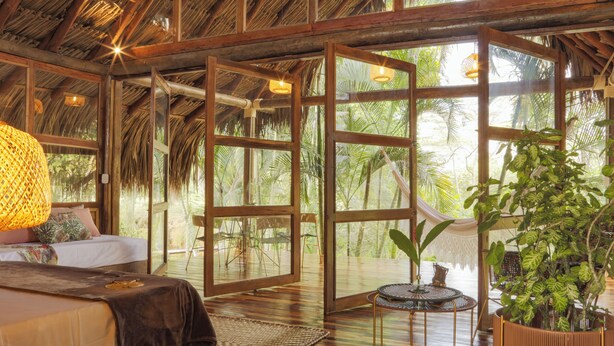 A spacious room with a wooden ceiling, large windows, and a bed with a brown bedspread. - Hacienda Boutique  (Restrepo)